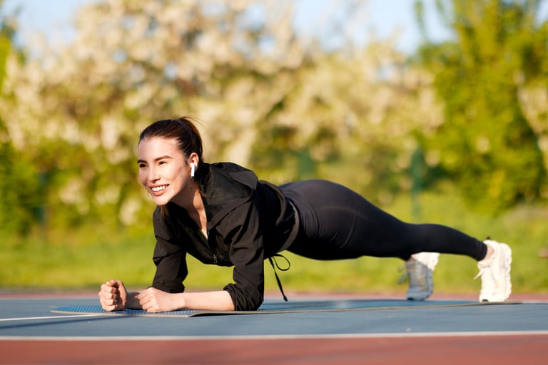 Young woman confidently holding a plank pose on a mat in an outdoor park setting